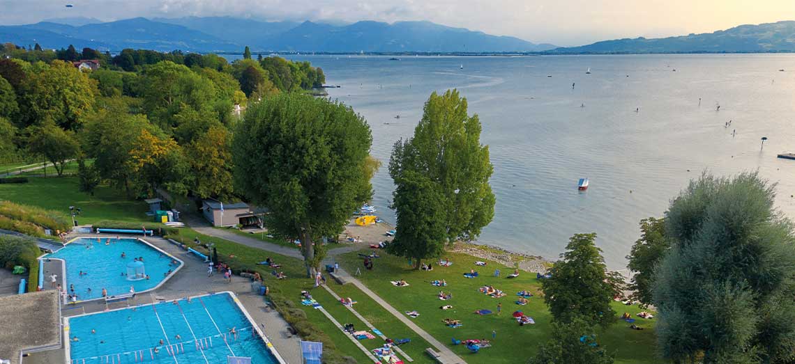 Blick auf das Freibad Aquamarin, den Bodensee und die Alpen